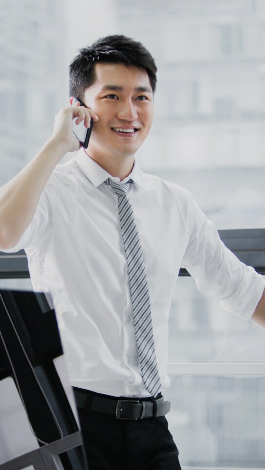 携帯電話を耳に当てたまま笑っている男性