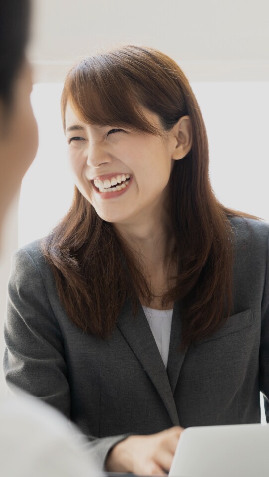 前に立っている男性の姿を眺めながら微笑んでいる女性
