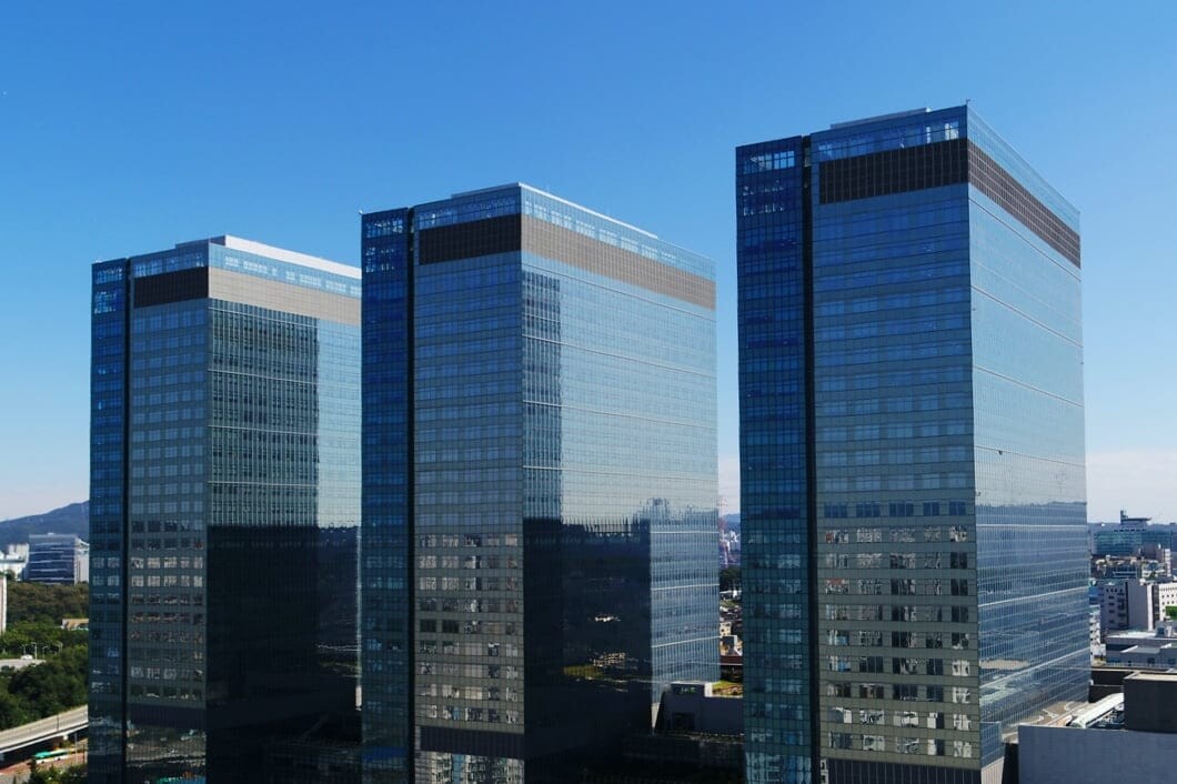 Three glass-facade skyscrapers stand under a blue sky.
