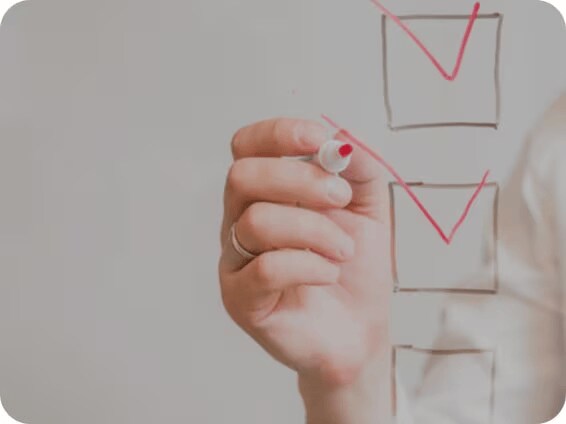 Hand marking items on a checklist with a red marker